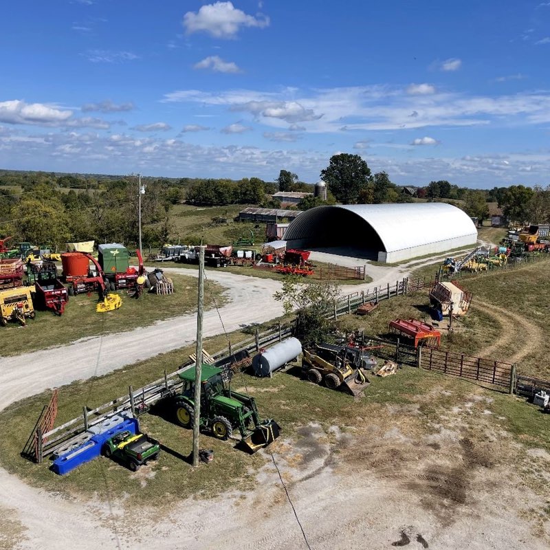 A white Q Series Quonset hut on a working farm, surrounded by tractors and farm equipment
